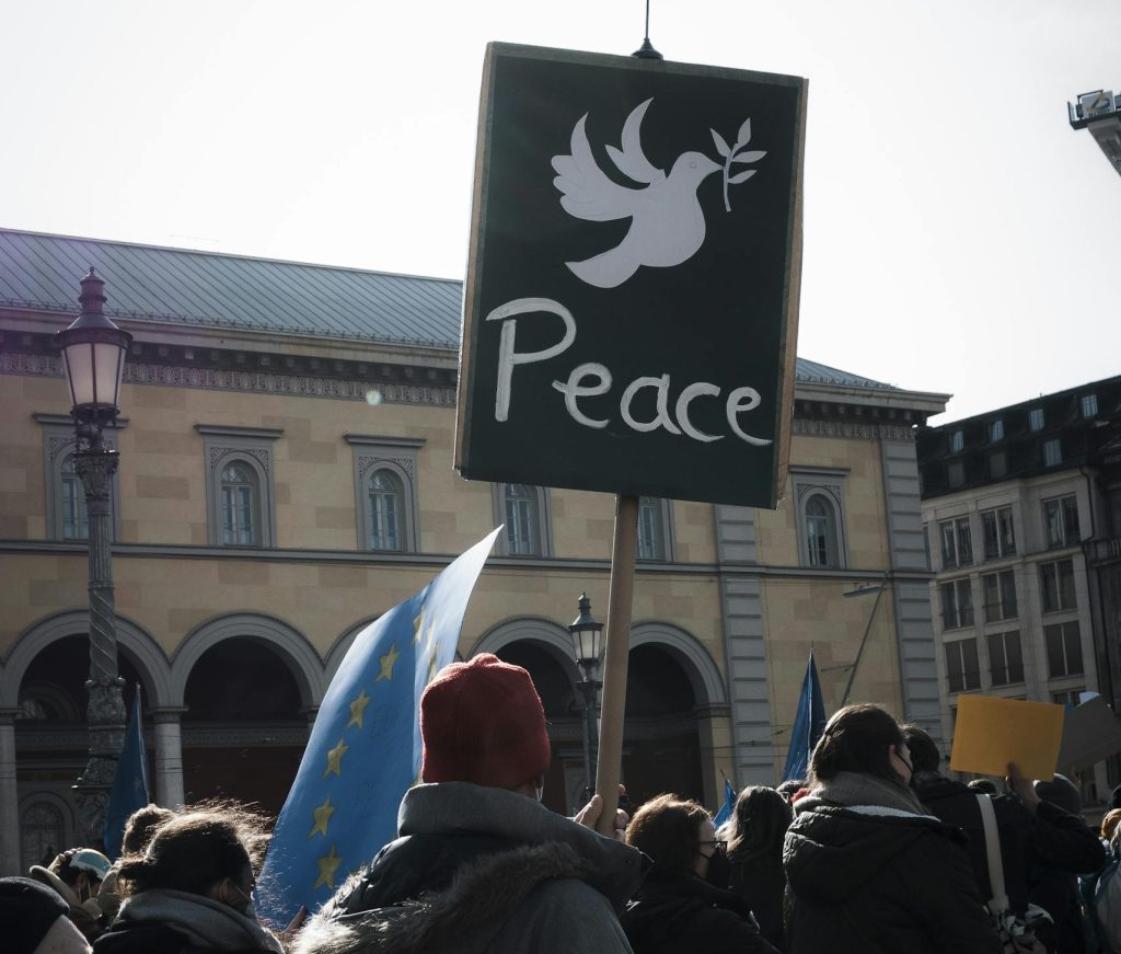 A crowd in Munich holds a peace sign during a peaceful protest in the city square.