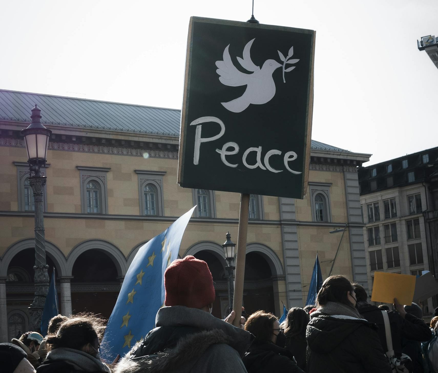 A crowd in Munich holds a peace sign during a peaceful protest in the city square.