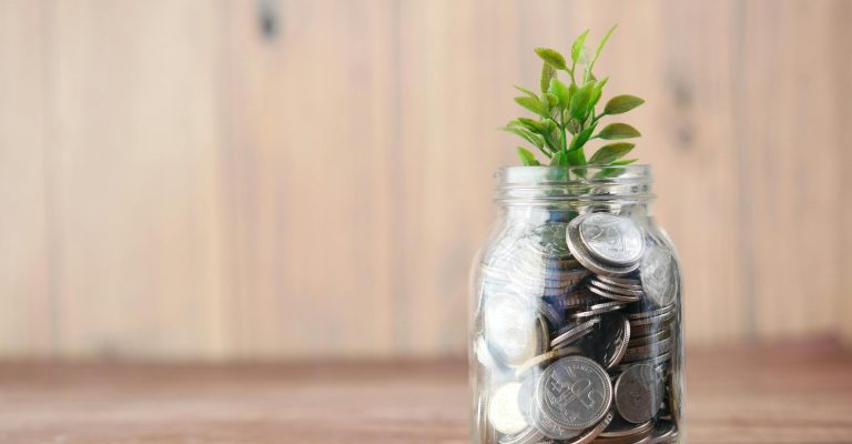 A jar filled with coins and a plant symbolizes growth in savings and investment.