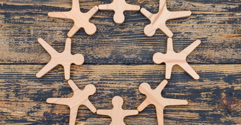 Marketing concept with wooden figures of person stand in circle on wooden background flat lay.